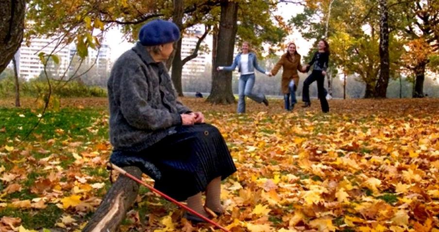 Пожилая женщина оголяется в саду под деревом 