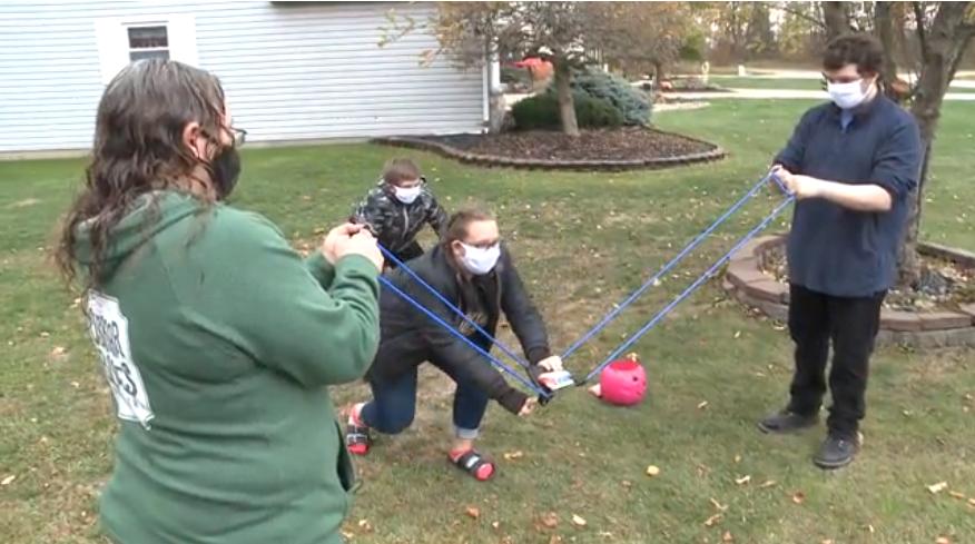 Координация и безопасность: женщина из Огайо использует большую рогатку, чтобы раздавать лакомства детям