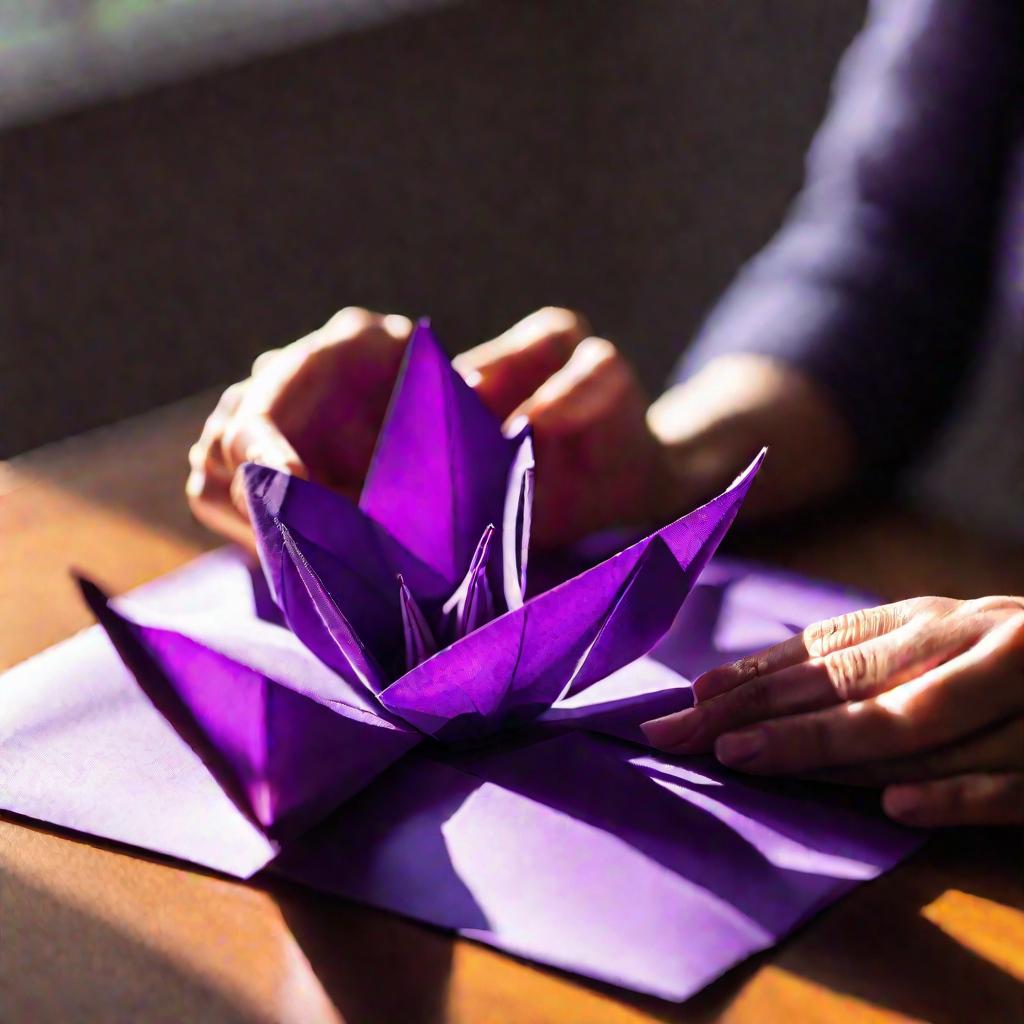 Руки складывают лист бумаги в лилию оригами