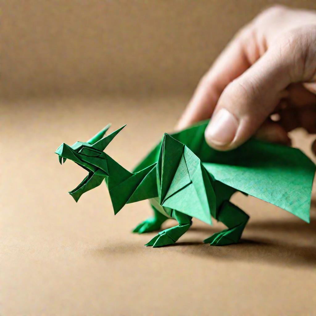 Крупный план ловких рук, аккуратно складывающих зеленого оригами дракона из фактурной бумаги.