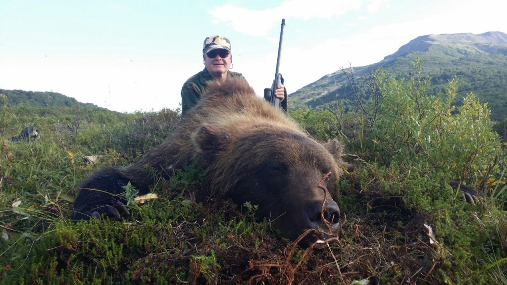 Охотник рядом со своей добычей-медведем