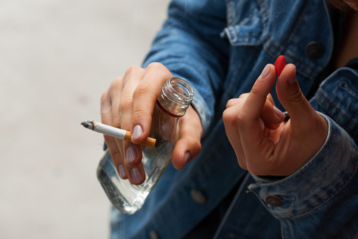 подросток с сигаретой, бутылкой и таблеткой