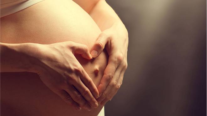 Беременная девушка держит живот