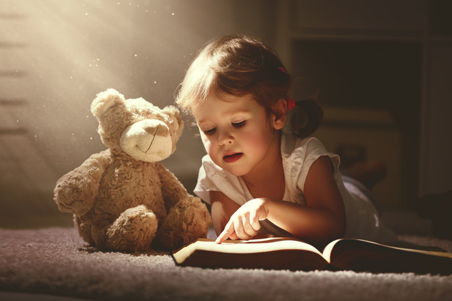 Девочка читает книгу мишке