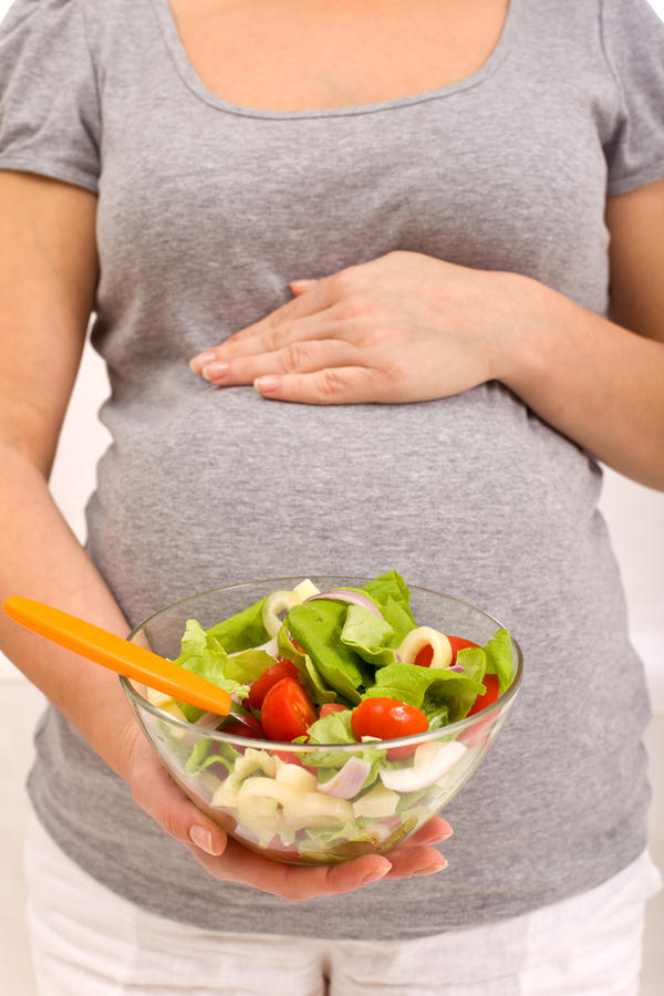 Беременная держит в руках салат