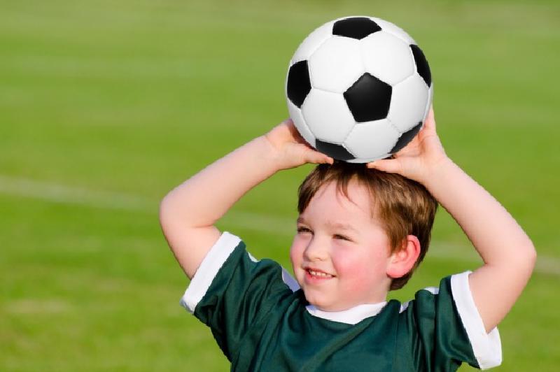 Ребенок проиграл. Мальчик подбрасывает мяч вверх. Фото взрослых детей с футбольным мячом на белым фоне. Матчу можно детям