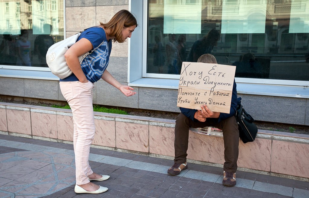 Стоит прилично. Просит денег. Попрошайки на улицах. Попрошайки денег на улице. Попрошайка с табличкой.