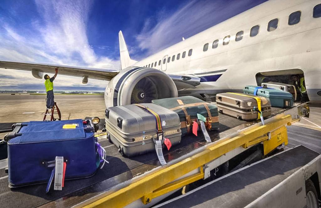 Самолет на летном поле аэропорта грузит багаж