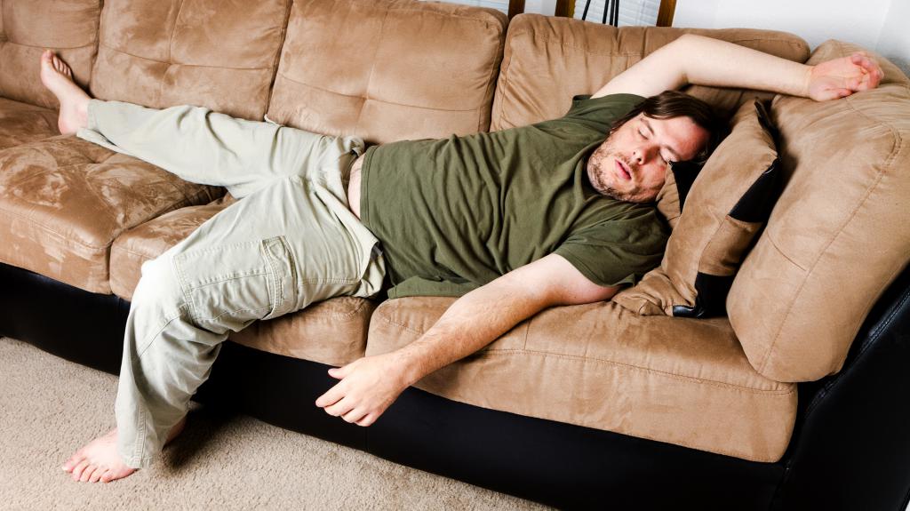 Человек, которому не помешал бы спортзал, лежит на диване
