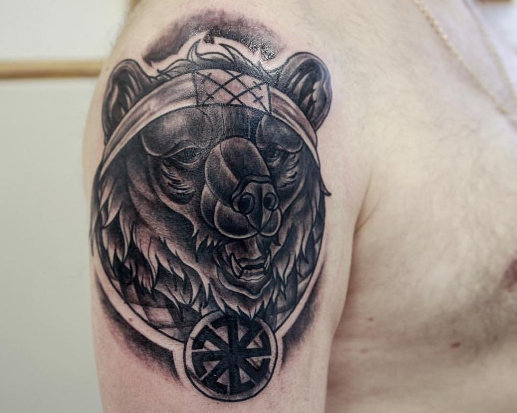 татуировка на плече у парня "медведь и коловрат"