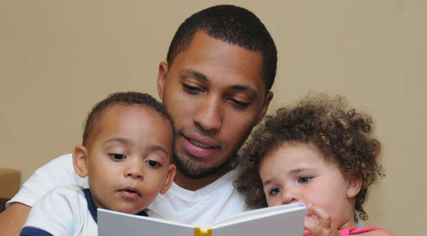 мужчина читает детям книгу