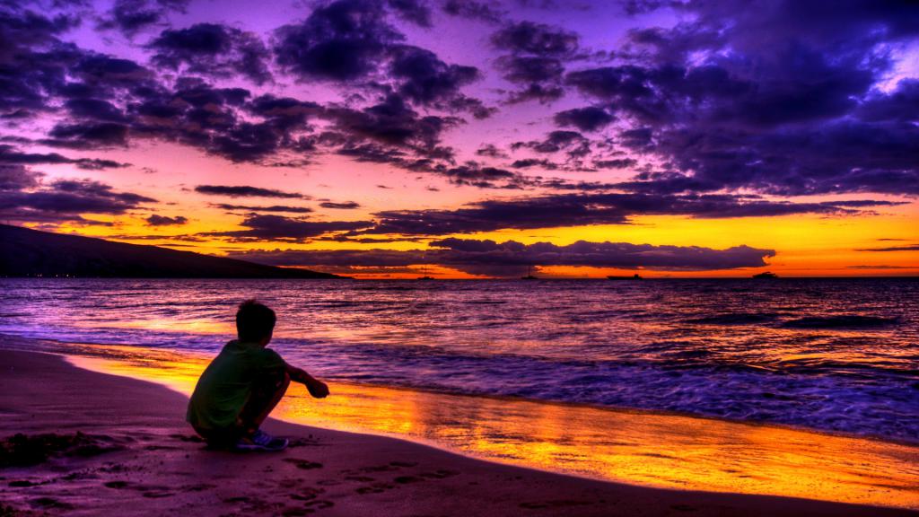 Мальчик сидит около океана
