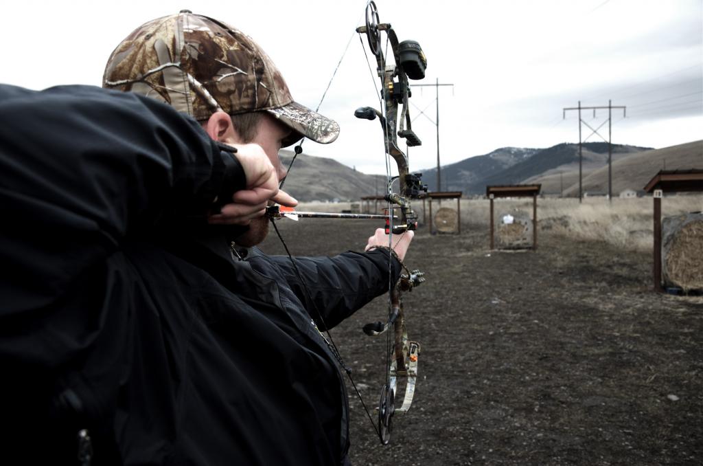 A man shoots from a hunting bow equipped with a scope