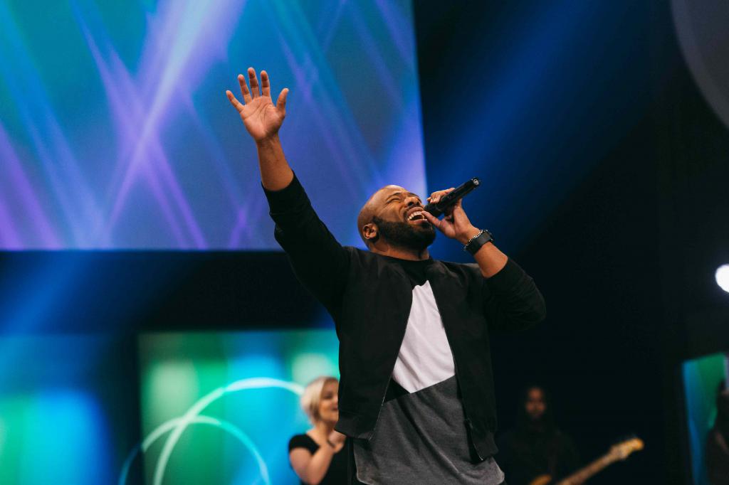 A man with a microphone and a raised hand