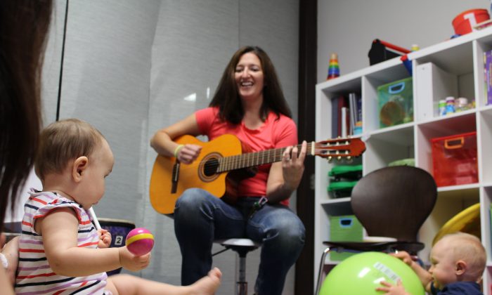 женщина играет на гитаре перед детьми