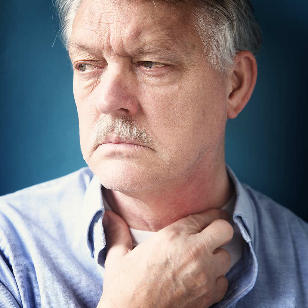мужчина держится за горло в области щитовидки