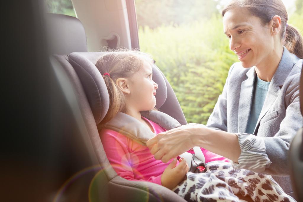 woman sits a girl in a car seat