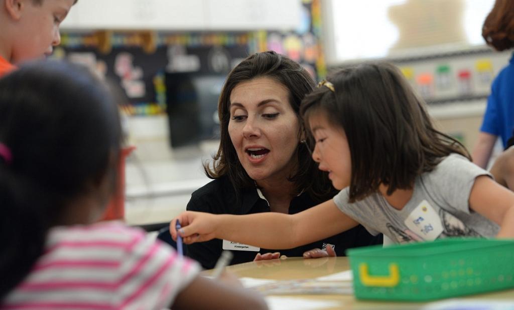 girl shows teacher what is written on paper