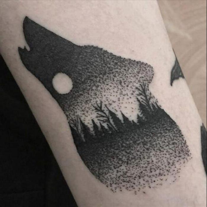 tattoo of a wolf howling to the moon on his back