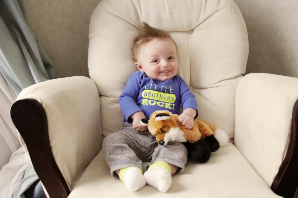 A child with a toy sits in a chair